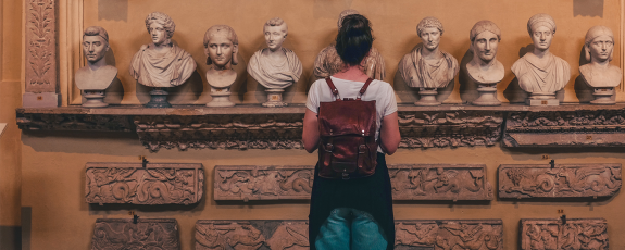 Female student examining stone busts in a museum